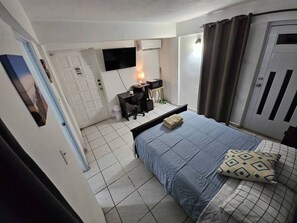 Une chambre à coucher comprenant un lit, un bureau, une chaise, une télévision et une armoire.