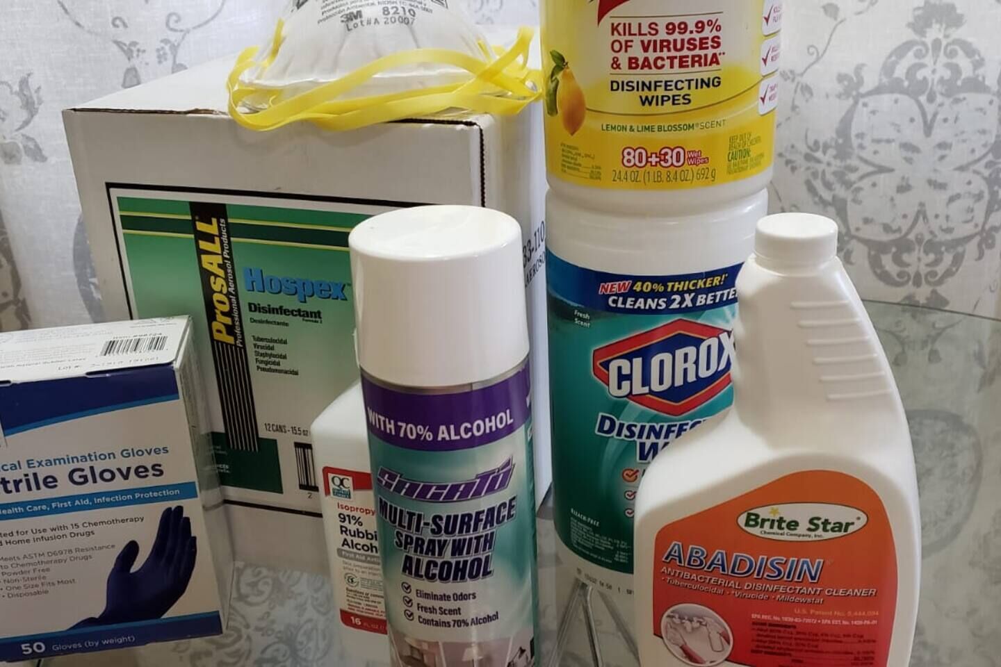 A collection of medical supplies including gloves, disinfectant wipes, and a spray bottle.