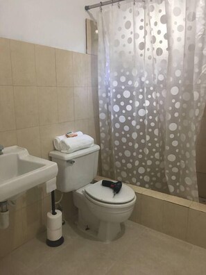 Ein Badezimmer mit Toilette, Waschbecken und einer Duschvorhang mit Punkten.