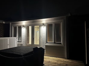A dark room with a table and chairs, a door with a mirror, and a light fixture above the door.