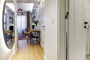 Ein modernes Interieur mit Essbereich, einem Spiegel und einem Flur, der zu einem Zimmer mit einem Bett führt.