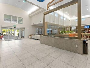 Eine geräumige Lobby mit einer Rezeption, einer Glastrennwand und einer Tür mit der Beschriftung 'EXIT'.