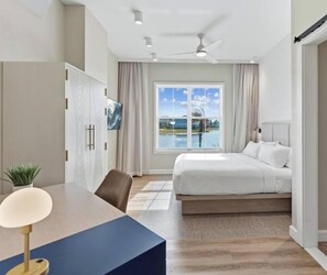 Ein Schlafzimmer mit Bett, Schreibtisch, Stuhl, Deckenventilator und einem Fenster mit Blick.