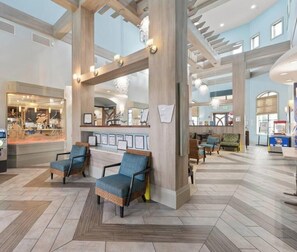 Eine geräumige Lobby mit Sitzgelegenheiten, einem Fahrkartenschalter und Blick auf ein Restaurant.