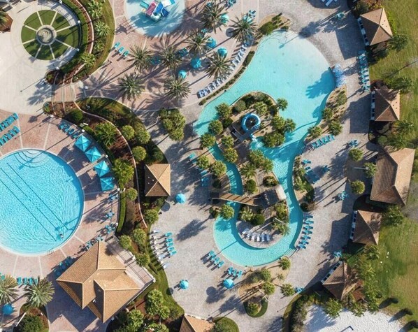 Eine Luftaufnahme eines Resorts mit mehreren Schwimmbecken, Liegebereichen und Palmen.