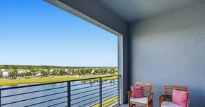 Ein Balkon mit zwei Holzstühlen und Blick auf ein Gewässer sowie Gebäude.