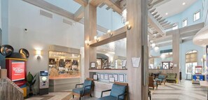 Eine geräumige Lobby mit Sitzgelegenheiten, einem Fahrkartenschalter und Blick auf ein Restaurant.