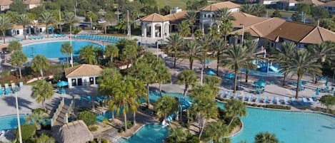 A resort with multiple swimming pools, palm trees, and a view of the surrounding residential area.