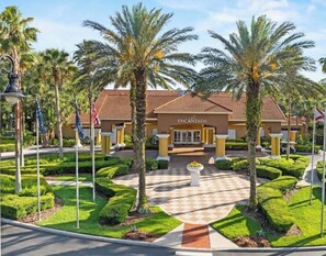 A hotel entrance with palm trees, a checkered pathway, and a central planter. - 3063 Townhouse Hot Tub Resort Pools near Disney (Kissimmee)