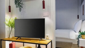 A modern living room with a flat-screen TV on a wooden table, a sofa, and a small side table with a plant. - Magical 2 Bedroom Apartment At Monnas Suite (Beyoglu)
