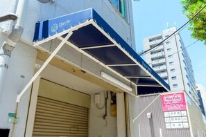 Ein Gebäude mit einer blauen Markise, auf der 'Darin Hotel' steht, einer geschlossenen Rolltür und einem Schild von MaxValu Express.