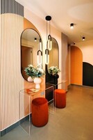 Un interno moderno con un grande specchio, pareti divisorie in vetro trasparente e sgabelli arancioni.