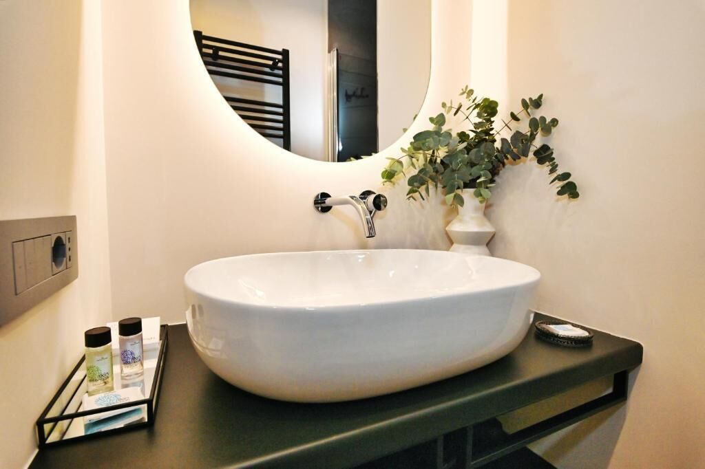A bathroom with a white sink, a mirror, a towel rack, and a potted plant.