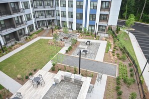 Une cour avec des espaces de détente en plein air, un coin barbecue et un parking.