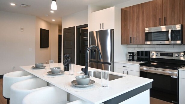 A modern kitchen with a central island, stainless steel appliances, and white cabinetry.