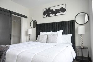 Une chambre à coucher comprenant un lit, une armoire, une table de chevet, une lampe et un miroir fixé au mur.