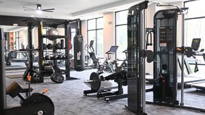 A gym with various exercise equipment, including a squat rack, weight bench, and cardio machines.