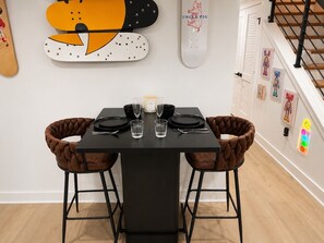 Een eettafel met zwarte stoelen, een kaars en een skateboard met 'UNCLE PIG' op de muur.