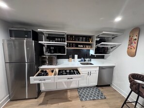 Een kleine keuken met inbouwapparatuur, open planken en een vloerkleed met een patroon.