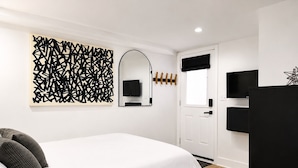 Une chambre moderne avec un lit, une télévision, un miroir et un élément décoratif mural.