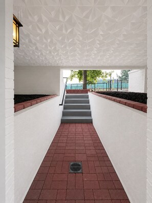 A covered walkway with geometric ceiling design, red brick steps, and a metal grate on the floor. - Boutique Retreat - apartment in DC - Sleeps 6 (Washington)