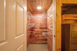 A wooden-paneled room with a white door, a ceiling light, and metal shelves. - Ligonier Relaxing Country 2 Bedroom Ranch – Fallen Oak,  
Sauna, Cold Plunge, MC (Ligonier)