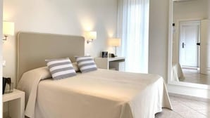 A hotel room with a large bed, bedside lamps, a nightstand, and a mirror. - Hotel Capanni (Bellaria-Igea Marina)