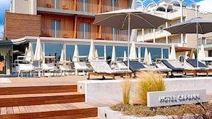 A hotel with a modern facade, outdoor seating area with umbrellas, and a sign indicating the hotel's name. - Hotel Capanni (Bellaria-Igea Marina)