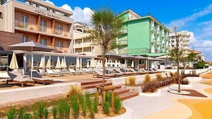 A hotel with a pool area, sun loungers, and a building with balconies. - Hotel Capanni (Bellaria-Igea Marina)