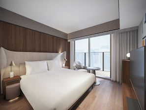 A modern hotel room with a large bed, a bedside table with a lamp, a small round table, and a view of the city through large windows. - Mitsui Garden Hotel Osaka Dojimahama PREMIER (Osaka)