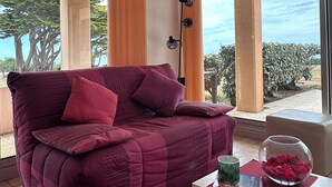 A room with a purple sofa, a glass fishbowl on a table, and a view of the outdoors. - Ground-floor apartment facing the sea with a large terrace (Pornic)