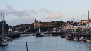 A harbor with boats, a castle on a hill, and buildings along the waterfront. - Ground-floor apartment facing the sea with a large terrace (Pornic)