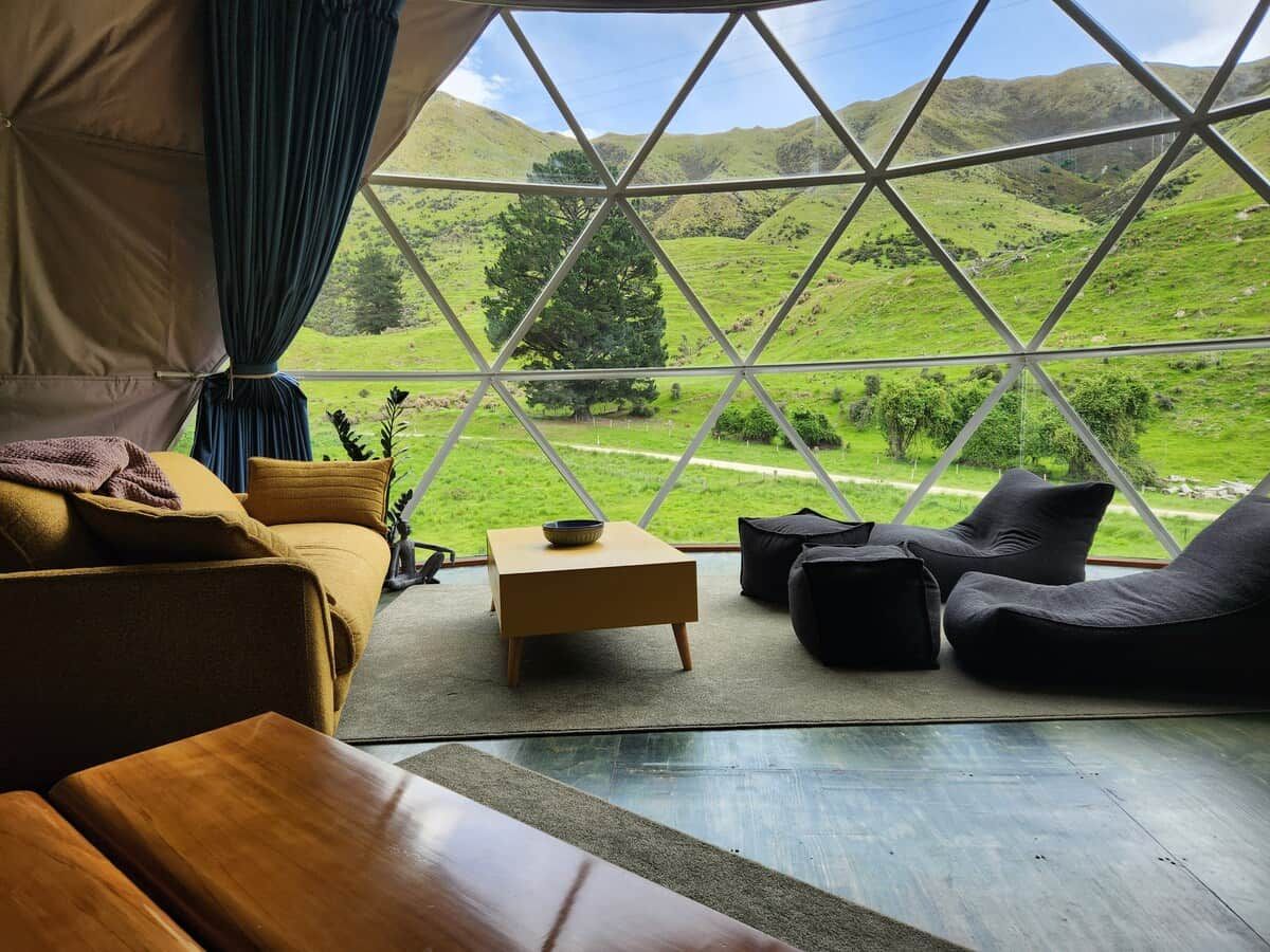 A cozy room with a large window, a sofa, a small table, and a bean bag.