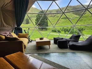 A cozy room with a large window, a sofa, a small table, and a bean bag.