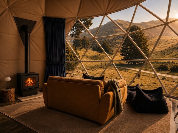 A cozy room with a sofa, a fireplace, and a view of a mountainous landscape.