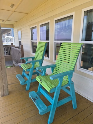 Eine überdachte Veranda mit zwei türkisfarbenen Adirondack-Stühlen und einem Holztisch.