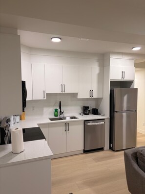 A modern kitchen with white cabinets, stainless steel appliances, and a dishwasher. - Nice and comfortable home away from home. (Edmonton)