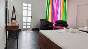 Una habitación de hotel con una cama, dos sillas, un escritorio y una puerta con ventana.