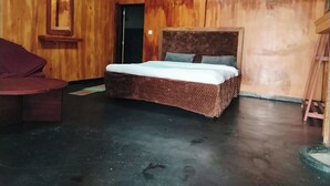 Una habitación con cama, una silla y pared de madera.