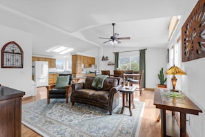 Ein geräumiges Wohnzimmer mit einer Ledersofa, einem Esstisch und einer Küche im Hintergrund.