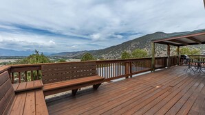 Una terraza de madera con un banco y una mesa, con vistas a un paisaje montañoso.