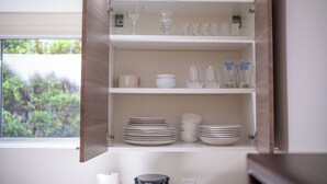 A kitchen cabinet with shelves containing plates, bowls, and glassware. - 3BR Dunbar Family Retreat Near UBC/Transit (Vancouver)
