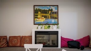 A living room with a fireplace, a painting, and a sofa with cushions. - 3BR Dunbar Family Retreat Near UBC/Transit (Vancouver)