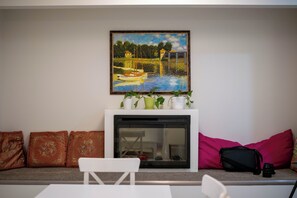 Ein Wohnzimmer mit Kamin, einem Gemälde und einer Couch mit Kissen.