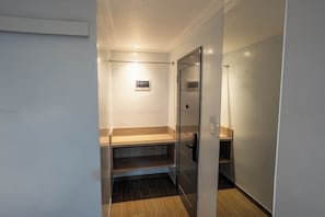 A narrow hallway with a glass door leading to a bathroom, wooden steps, and a small shelf with a picture. - Kuadro Hotel & Suites (Moalboal)