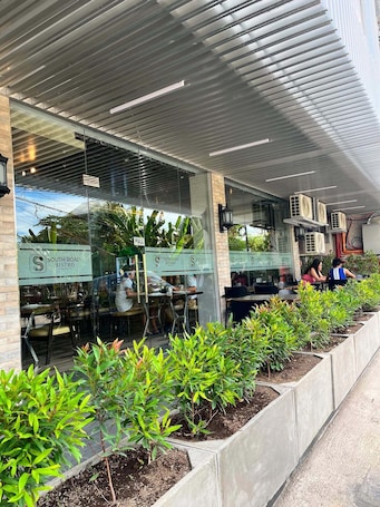 A modern restaurant with outdoor seating, a covered patio, and a clear view of the interior.