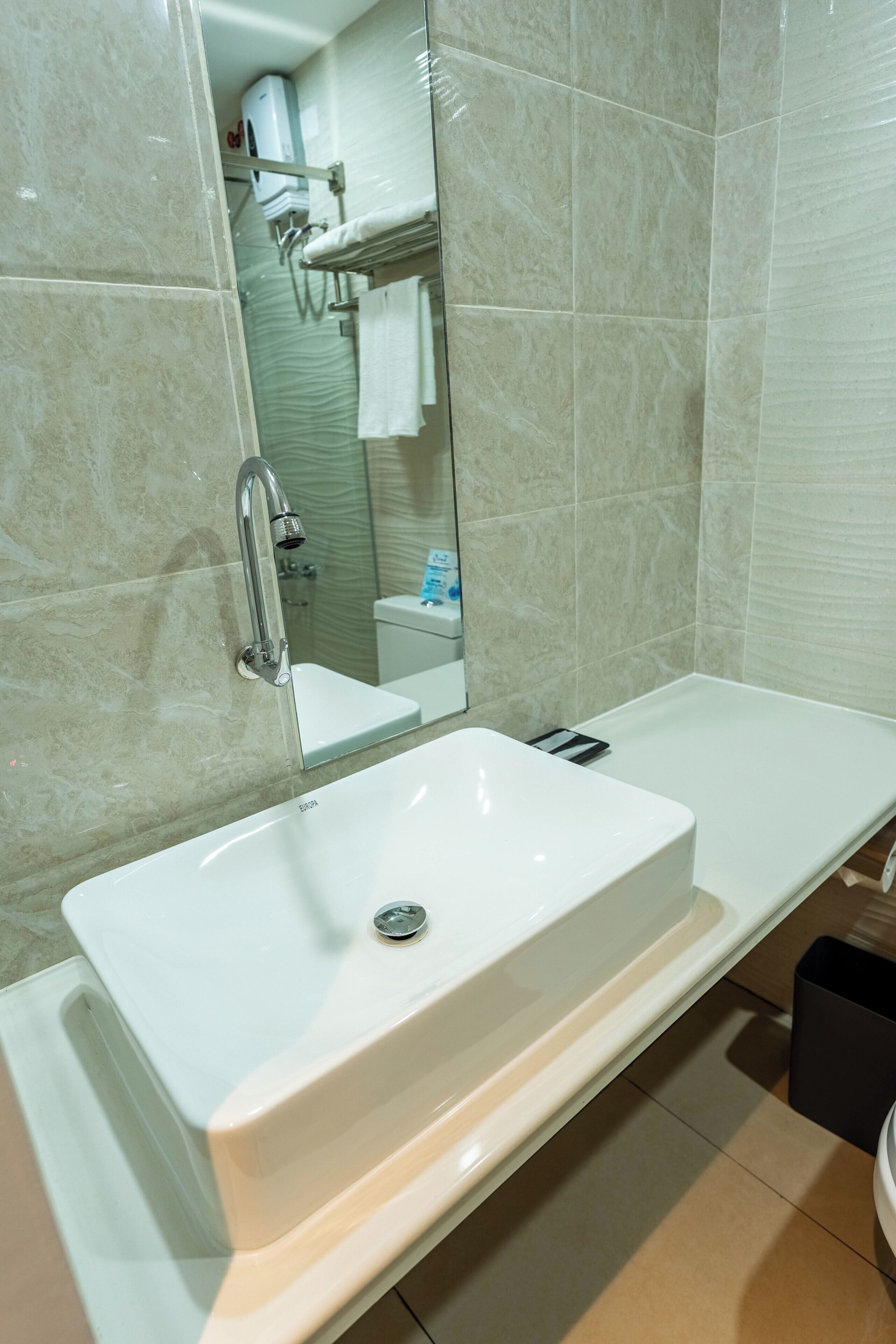 A bathroom with a white sink, a mirror, and a shower area.
