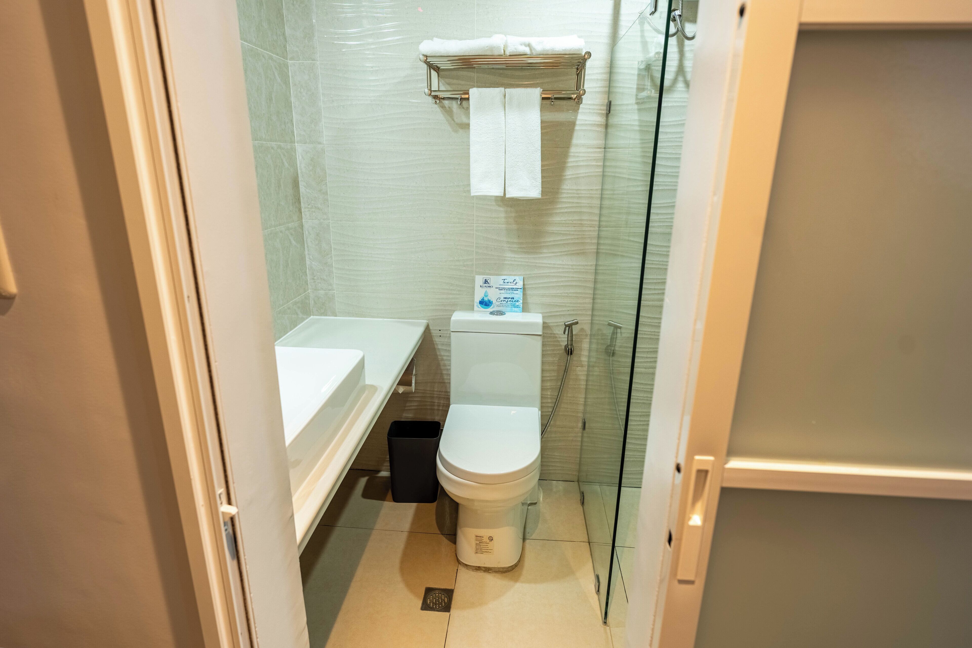 A small bathroom with a toilet, a sink, and a glass shower enclosure.