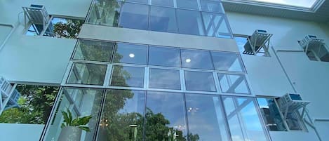 Un bâtiment moderne doté de grandes fenêtres en verre, d’un atrium central et d’une entrée bien visible.
