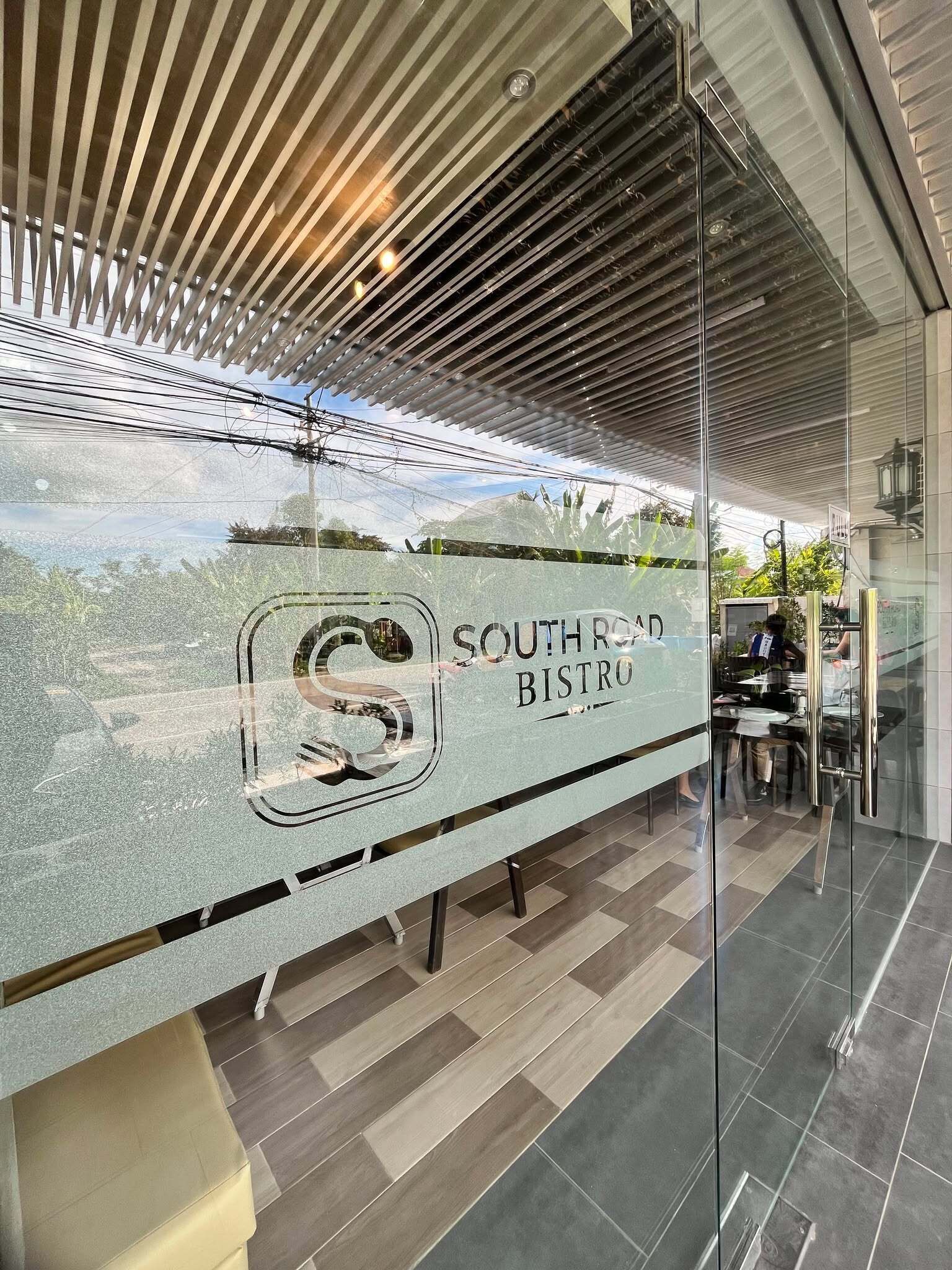 A modern bistro with a glass counter, a logo, and a view of greenery outside.